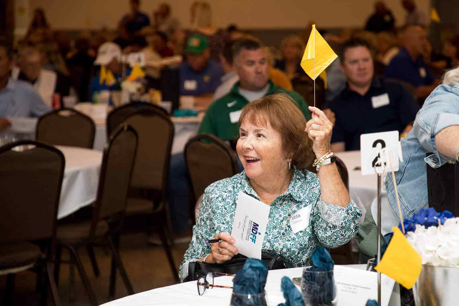 Attendee waving a yellow flag to bid at live auction